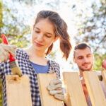 Two Happy People Painting Their Fence